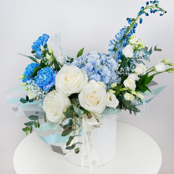 Blue/purple hydrangea - 2, Blue carnation - 4, White rose 50 cm - 4, lisianthus - 4, Colored gypsophila - 1, Round flower box small , Oasis, Wrapping Paper, Ruscus, Eucalyptus Cinerea, Blue Delphinium